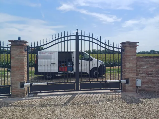 Cancello a due ante in ferro con attuatori e lampeggiante su un ingresso di campagna
