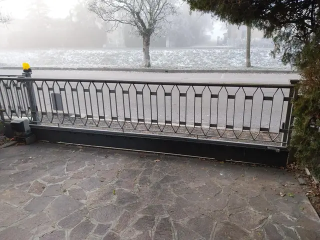 Cancello scorrevole automatico con lampeggiante e motoriduttore a cremagliera in una mattina di nebbia